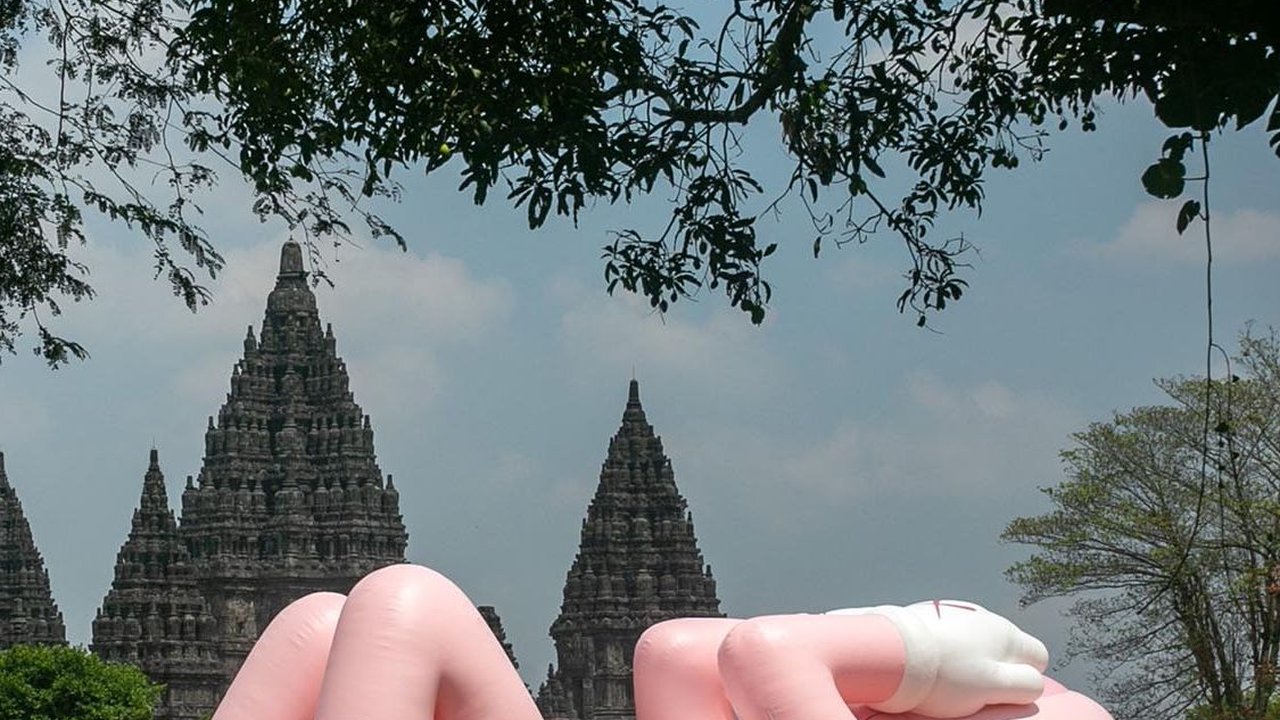 FOTO: Momen KAWS Liburan di Indonesia, Begini Potretnya Saat Asyik Rebahan di Candi Prambanan