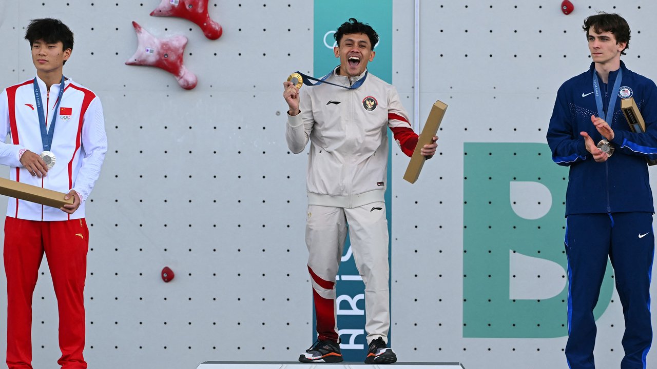 Atlet panjat tebing Indonesia, Veddriq Leonardo (tengah) melakukan selebrasi saat mendapatkan medali emas cabang olahraga pajat tebing nomor speed Olimpiade Paris 2024 di Le Bourget Sport Climbing Venue, Paris, Prancis, Kamis (08/08/2024). (AFP/Fabrice Coffriri)