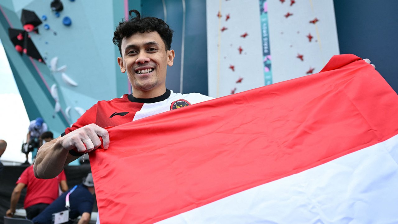 Atlet panjat tebing Indonesia, Veddriq Leonardo (tengah) melakukan selebrasi saat mendapatkan medali emas cabang olahraga pajat tebing nomor speed Olimpiade Paris 2024 di Le Bourget Sport Climbing Venue, Paris, Prancis, Kamis (08/08/2024). (AFP/Fabrice Coffriri)