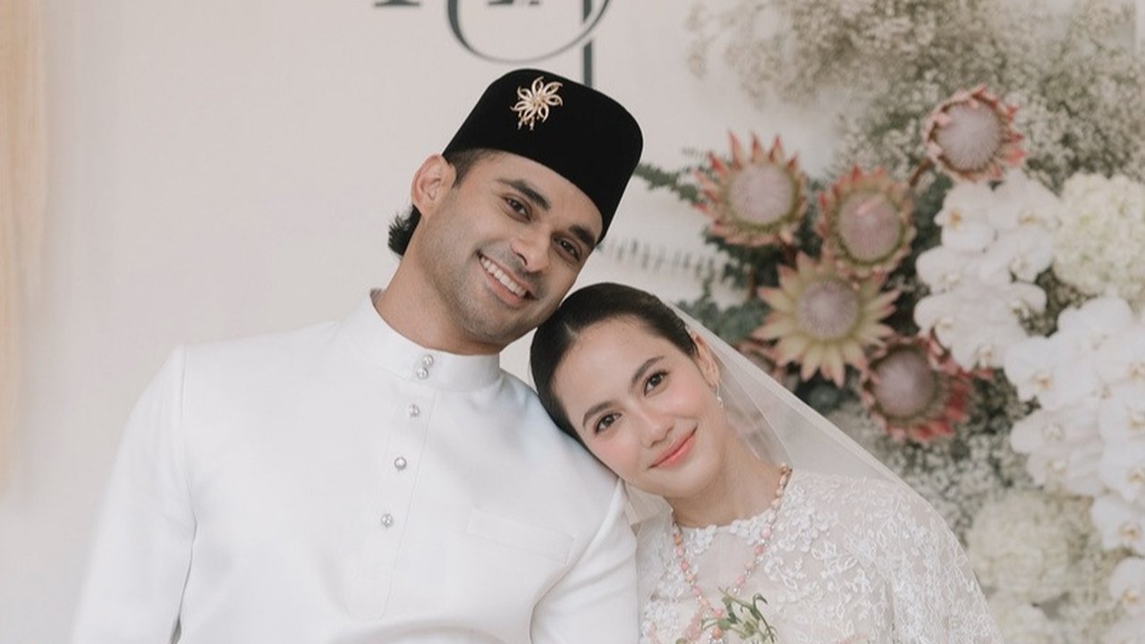 Sementara itu, mempelai pria mengenakan baju adat Melayu yang juga bernuansa serba putih, memberikan kesan elegan dan berwibawa.