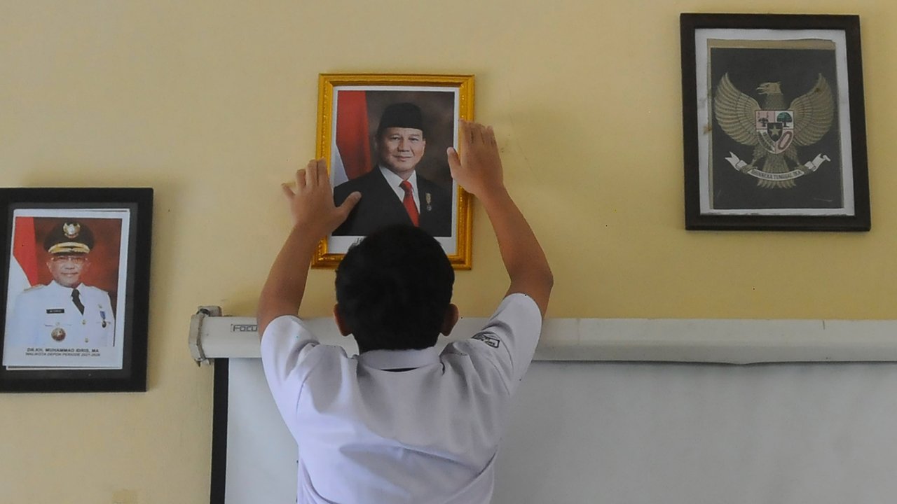 Murid pasang foto Presiden Prabowo di ruang kelas di SMPN 2 Depok, Jawa Barat, Senin (21/10/2024).