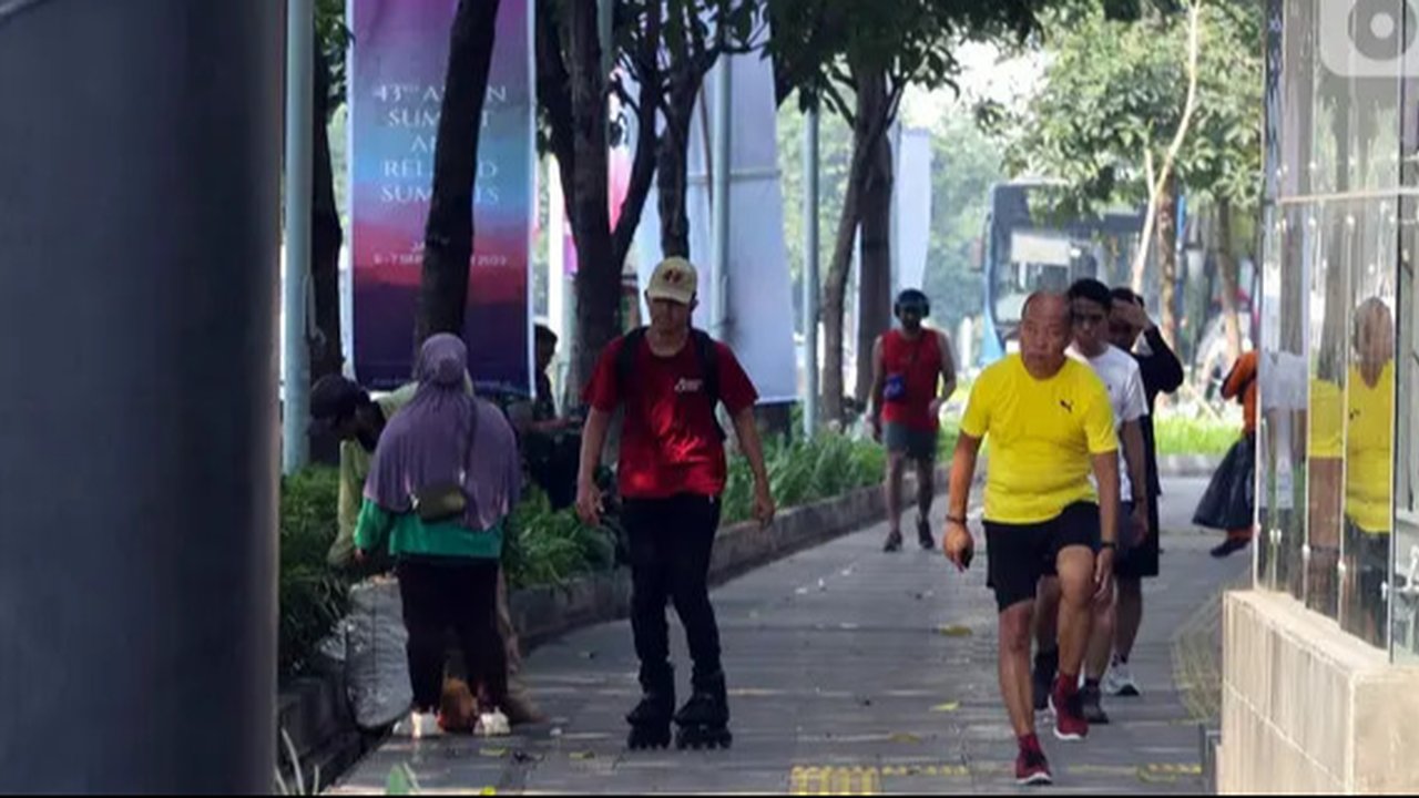 Siluet pekerja berjalan kaki di sepanjang Jalan Jenderal Sudirman, Jakarta, Senin (10/6/2024). (Liputan6.com/Herman Zakharia)