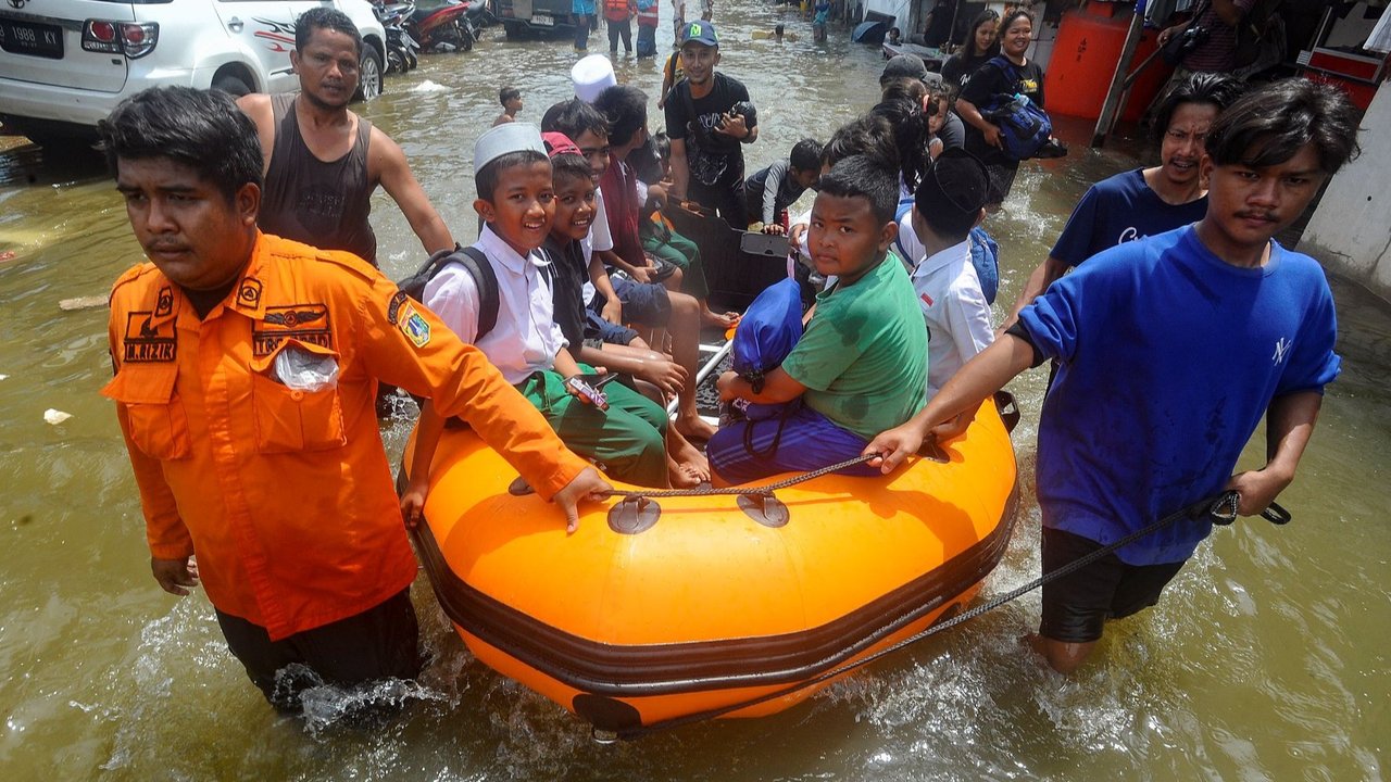 Petugas BPBD DKI mengevakuasi anak-anak pulang sekolah menggunakan perahu karet saat banjir rob menggenangi kawasan Muara Angke, Jakarta Utara, Senin (18/11/2024).