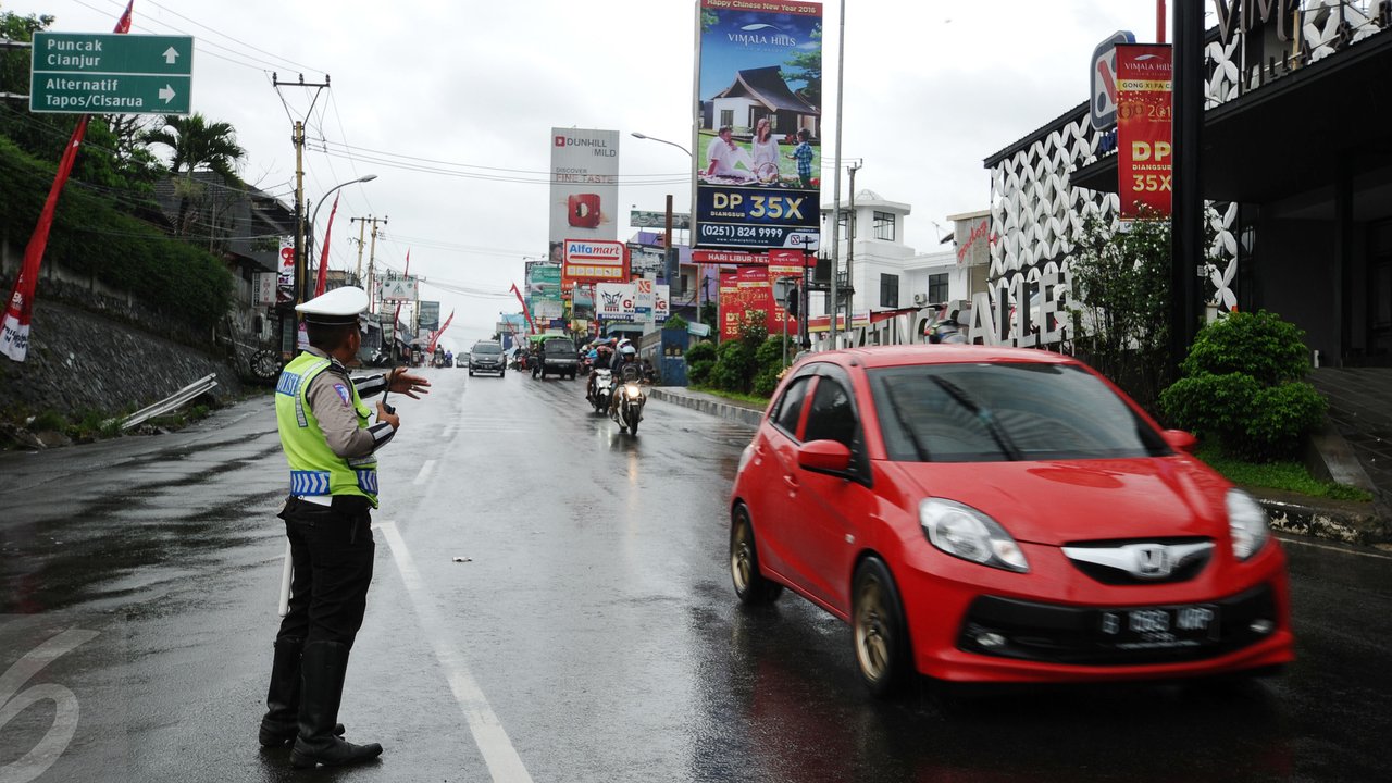 Petugas mengatur arus balik nenuju Jakarta jelang perempatan Gadog, Bogor, Senin (8/2/2016). Untuk mencegah kemacetan pasca libur panjang Tahun Baru Imlek 2016, Polres Bogor menerapkan buka tutup di jalur menuju puncak. (Liputan6.com/Helmi Fithriansyah)