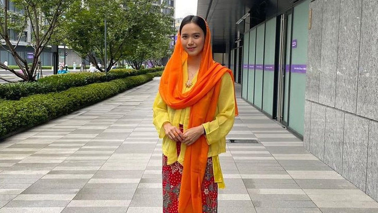 Kebaya dipadukan kerudung oranye serta kain batik merah sebagai bawahannya. Nadhira memadukan outfit tersebut dengan sneakers warna silver. [@indonesianationalwushuteam]