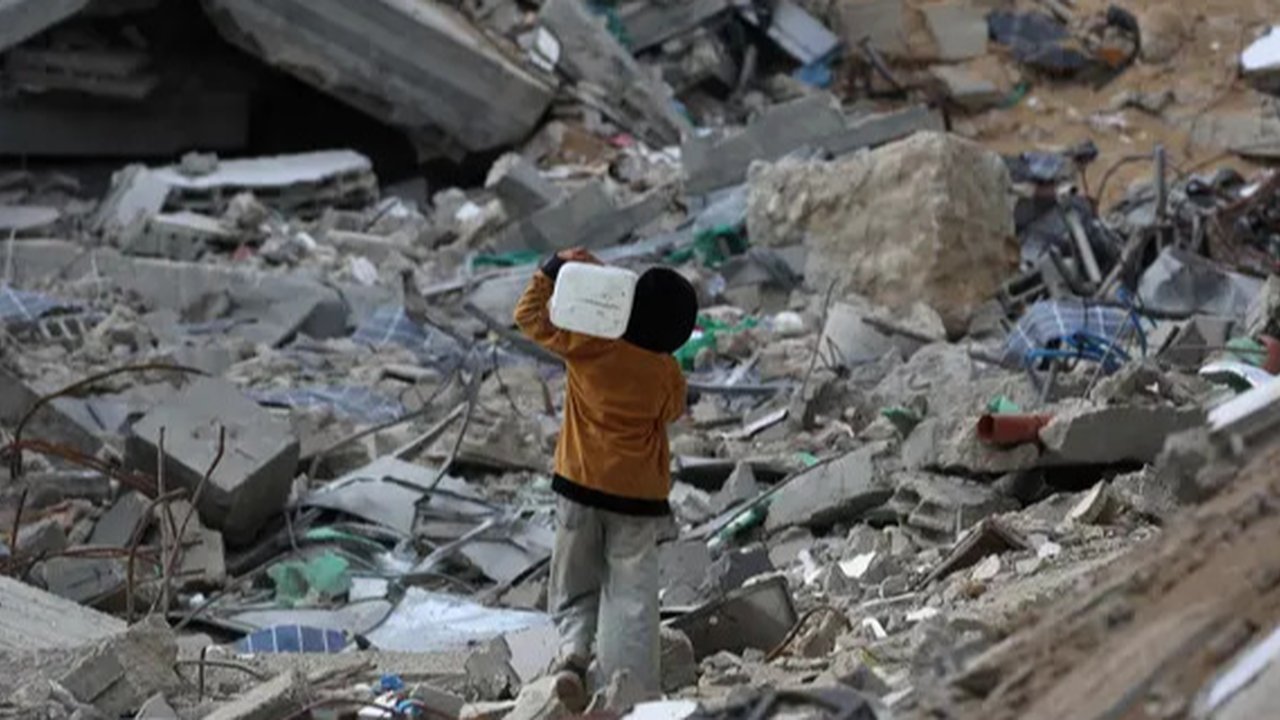 Saat ini jutaan anak masih menghadapi masalah-masalah yang sering membuat mereka merasa terancam hingga menimbulkan rasa takut. Tampak dalam foto, seorang anak laki-laki Palestina membawa sebuah wadah plastik saat dia berjalan melewati puing-puing di samping sebuah bangunan yang hancur akibat pemboman Israel baru-baru ini di Khan Yunis di Jalur Gaza selatan pada 19 November 2024. (Eyad BABA/AFP)