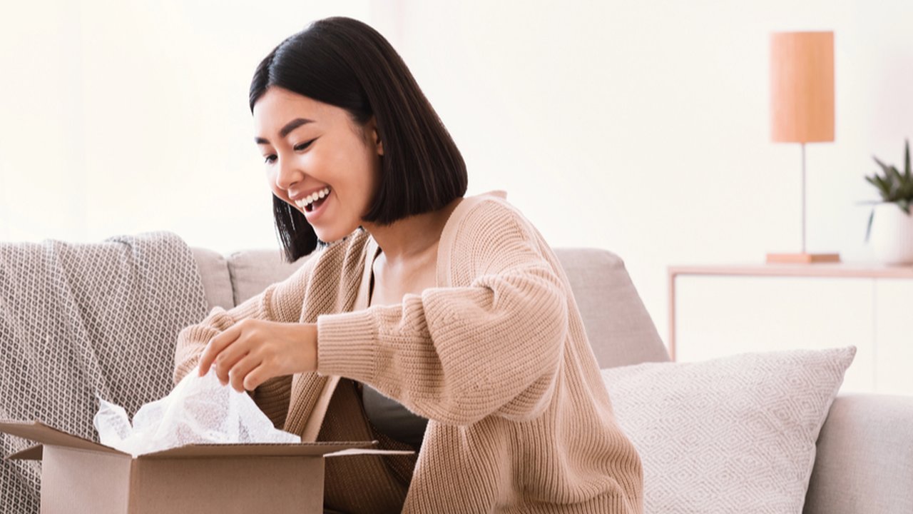 Ilustrasi perempuan membuka paket belanja online.