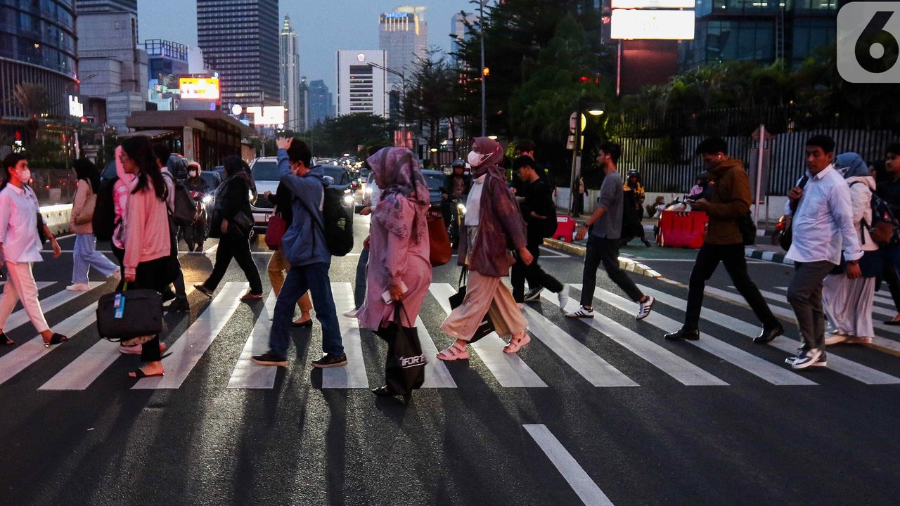Pekerja saat melintas trotoar di kawasan Jend Sudirman, Jakarta, Selasa (21/11/2023). (Liputan6.com/Herman Zakharia)