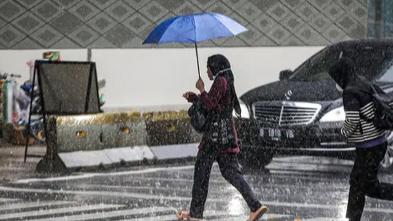 Warga menerjang hujan deras di kawasan Jalan Sudirman, Jakarta, Jumat (9/12/2022). Penjabat Gubernur DKI Jakarta Heru Budi Hartono menyebut pihaknya akan mengkaji penerapan bekerja dari rumah
