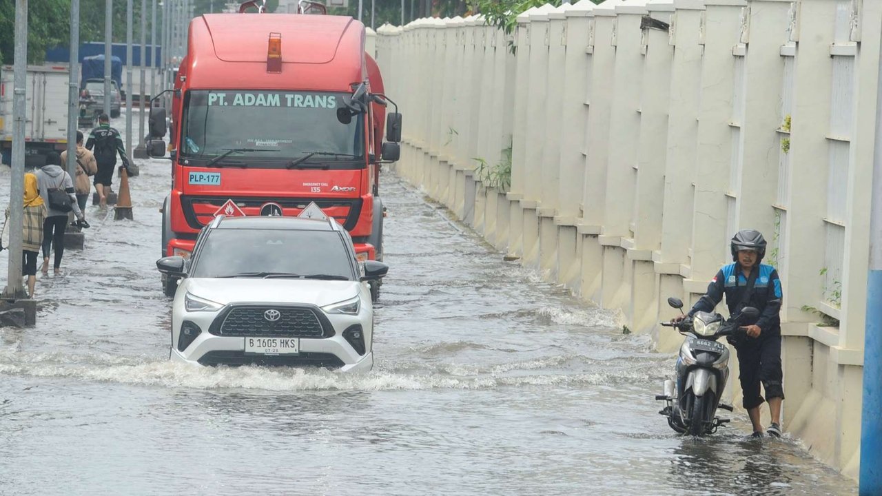 Warga membantu pengendara mobil mewah yang mogok terjebak saat banjir ob di Jalan PLTU Muara karang, Pluit, Jakarta, Senin (16/12/2024).