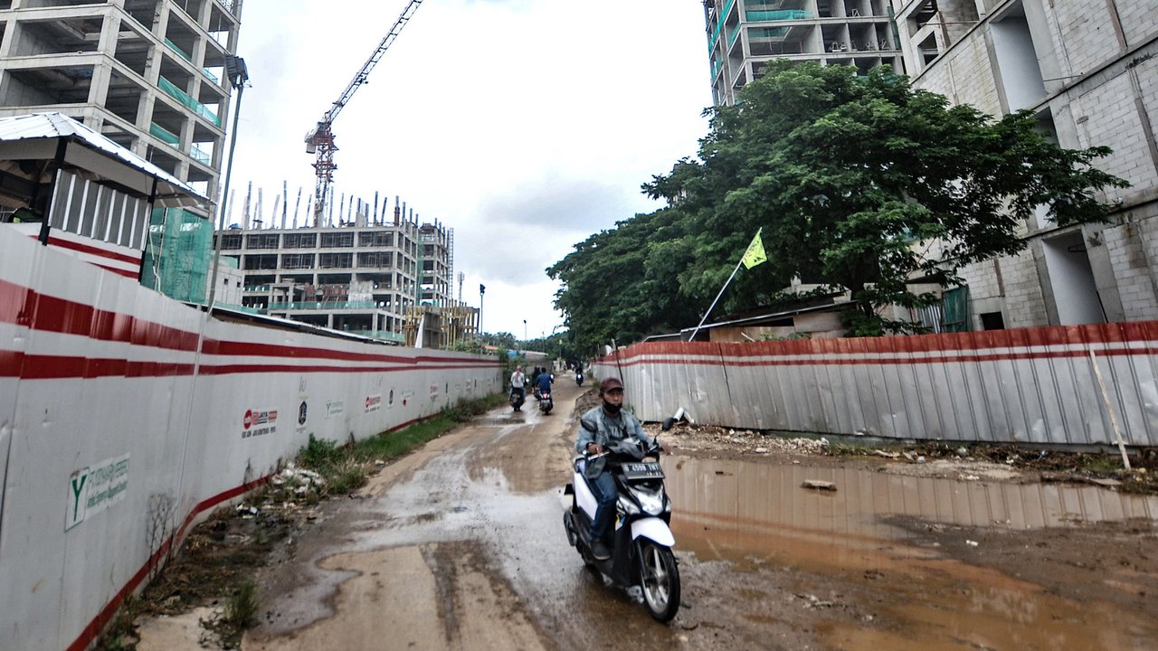 Warga melintas dekat proyek pembangunan rumah susun sewa (Rusunawa) PIK Pulogadung, Jakarta, Kamis (25/2/2021). Total nilai kontrak pembangunan 10 rusun multiyears untuk kontrak fisik menghabiskan anggaran Rp 2,2 triliun. (merdeka.com/Iqbal S. Nugroho)