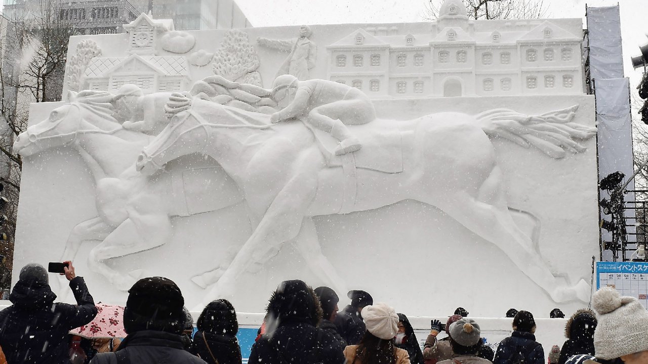 Sejumlah pengunjung melihat patung es balap kuda selama hari pembukaan Festival Salju Sapporo di Sapporo, Jepang (4/2). Festival salju Sapporo pertama kali diselengarakan tahun 1950. (AFP Photo/Jiji Press)