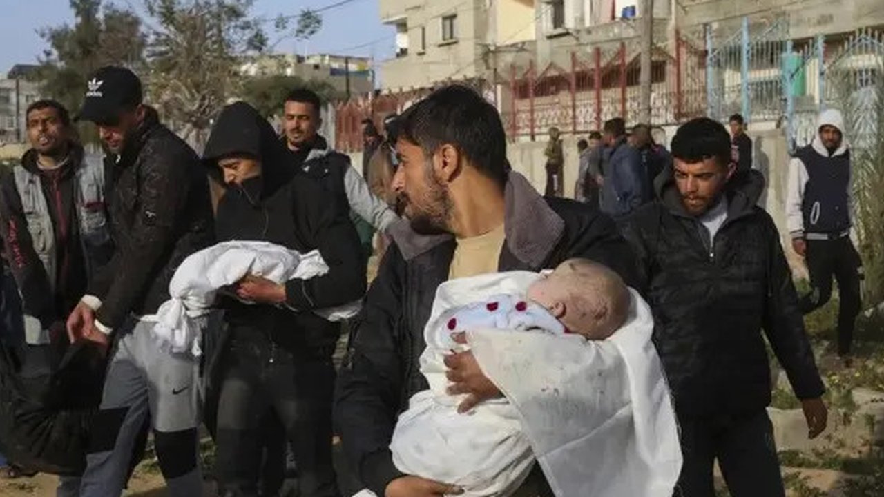 Seorang anak perempuan Palestina menunggu dalam antrean untuk menerima makanan di luar pusat distribusi di selatan Khan Yunis pada 6 Desember 2024. (BASHAR TALEB/AFP)