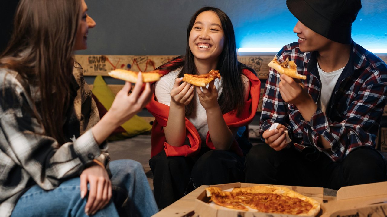 Kumpulan orang menyantap pizza.