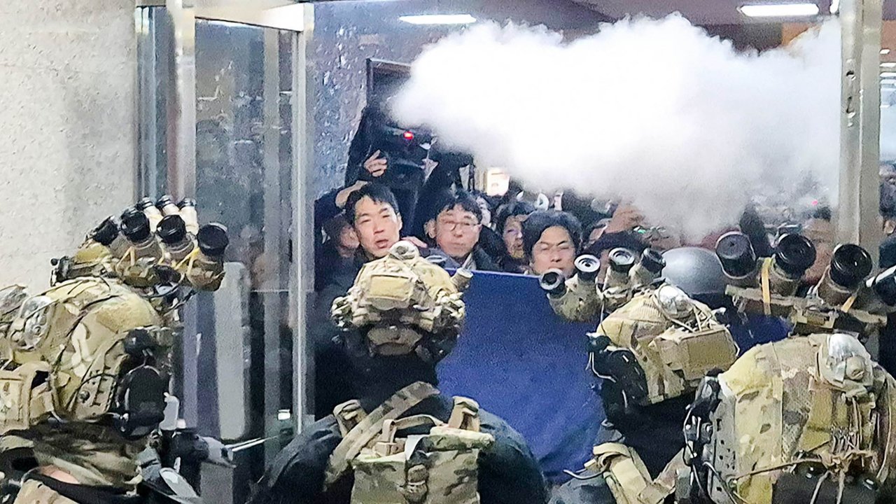 Seorang pria memegang bendera Korea Selatan di luar Gedung Majelis Nasional di Seoul (04/12/2024).
Foto  Anthony Wallace / AFP