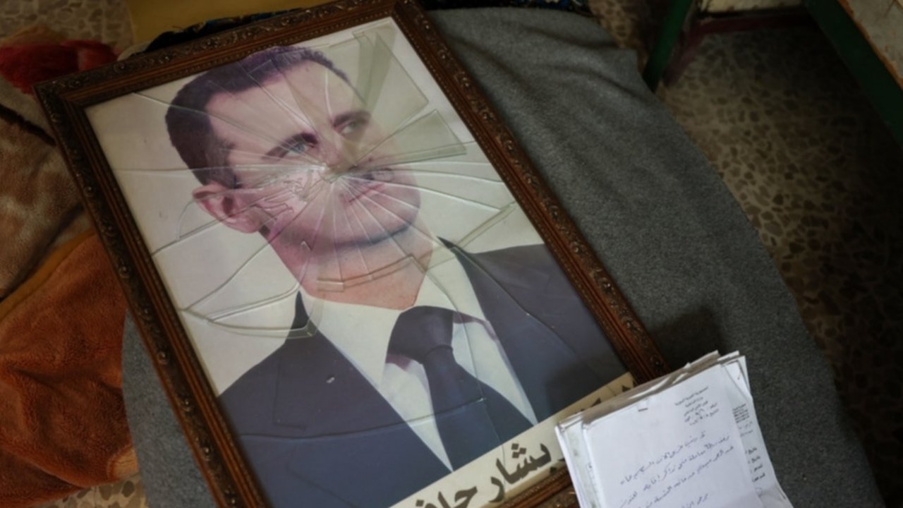 Seorang pria menginjak gambar presiden terguling, Bashar al-Assad, saat orang-orang memasuki kediamannya di daerah Malki, Damaskus, pada Minggu (8/12/2024), setelah pemberontak menyatakan