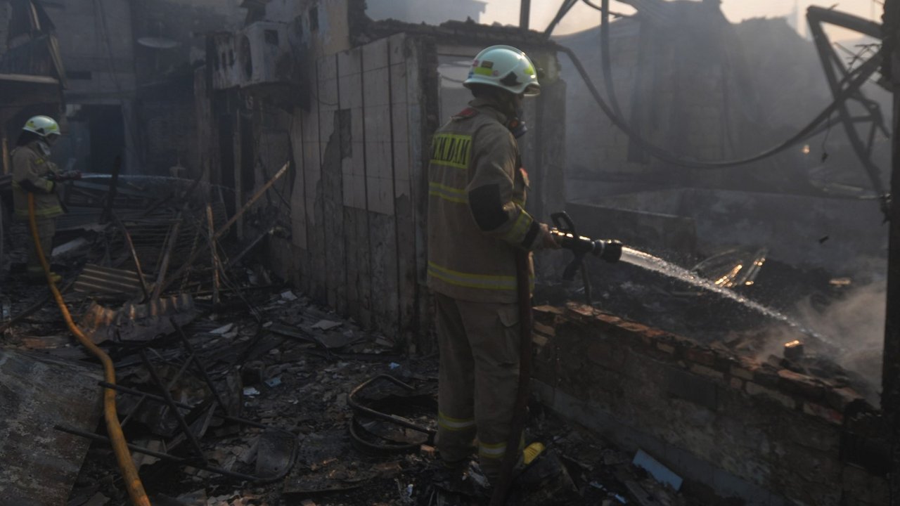 Petugas pemadam kebakaran melakukan pendinginan area pemukiman penduduk yang terbakar di Kawasan Manggarai, Jakarta, Selasa (13/8/2024).