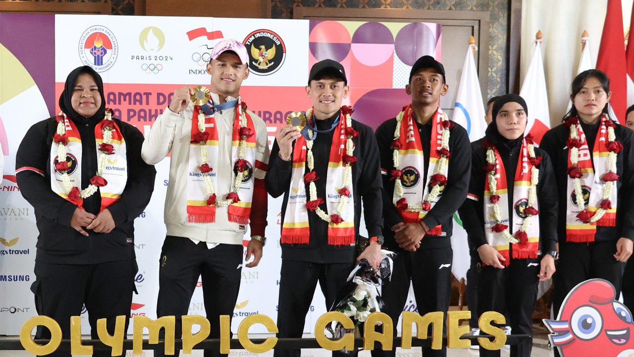 <p>Dua atlet Indonesia peraih medali emas di Olimpiade 2024 Paris: Rizki Juniansyah dan Veddriq Leonardo (tengah) bersama rombongan terakhir atlet Indonesia yang berjuang di Olimpiade 2024 usai tiba di Bandara Internasional Soekarno-Hatta, Tangerang, Selasa (13/8/2024). (Abdul Aziz/Bola.com).</p>