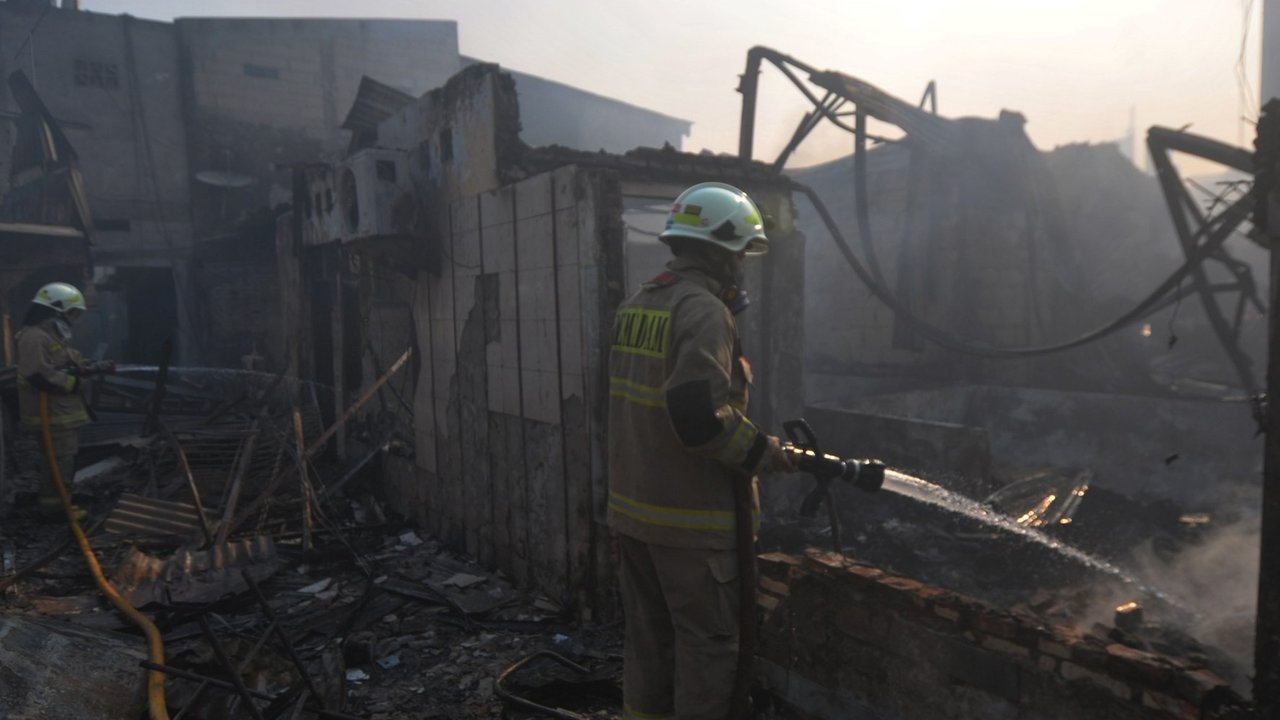 Petugas pemadam kebakaran melakukan pendinginan area pemukiman penduduk yang terbakar di Kawasan Manggarai, Jakarta, Selasa (13/8/2024).