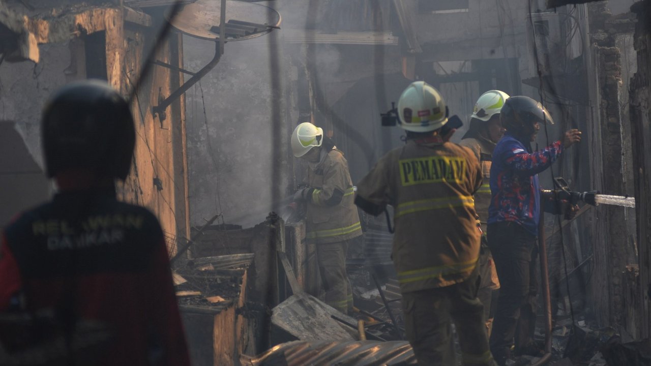 Petugas pemadam kebakaran melakukan pendinginan area pemukiman penduduk yang terbakar di Kawasan Manggarai, Jakarta, Selasa (13/8/2024).