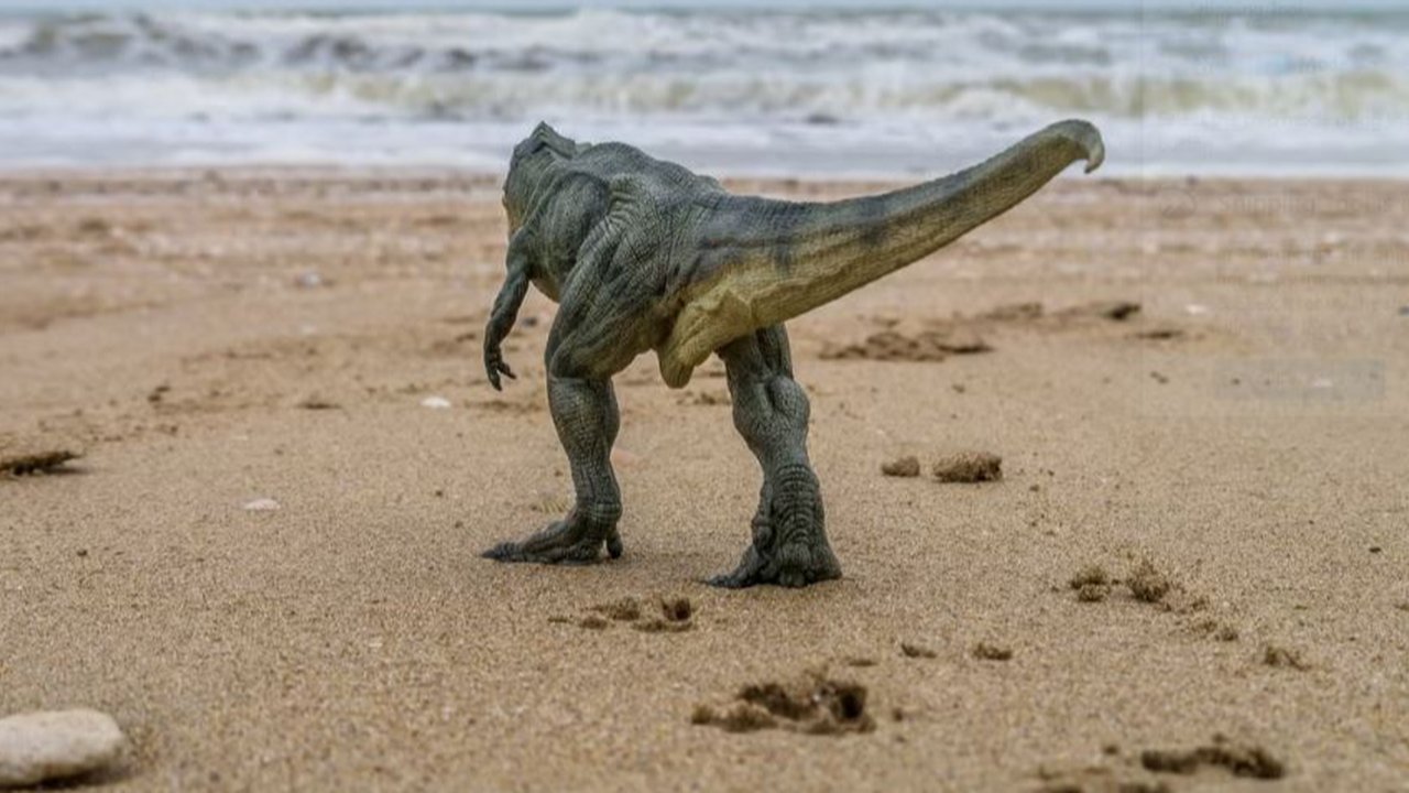 Ilustrasi dinosaurus berjalan di pantai.