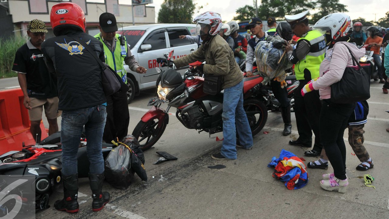 Petugas mencoba membantu menuntun motor akibat Kecelakaan yang terjadi di  jalan Lamaran, Karawang, Jawa Barat, Minggu (3/7). Kecelakaan kecil terjadi menimpa pemudik yang menggunakan sepeda motor di jalan Lamaran, Karawang. (Liputan6.com/Gempur M Surya)