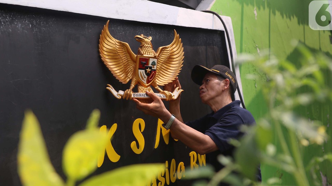 Anak-anak melintas membawa bendera merah putih berlatar belakang mural Pancasila di Kampung Pancasila, Karang Tengah, Kota Tangerang, Selasa (1/6/2021). Sejumlah kegiatan diadakan warga, Komunitas Taman Potret dan TNI ini untuk memperingati Hari kelahiran Pancasila. (Liputan6.com/Angga Yuniar)