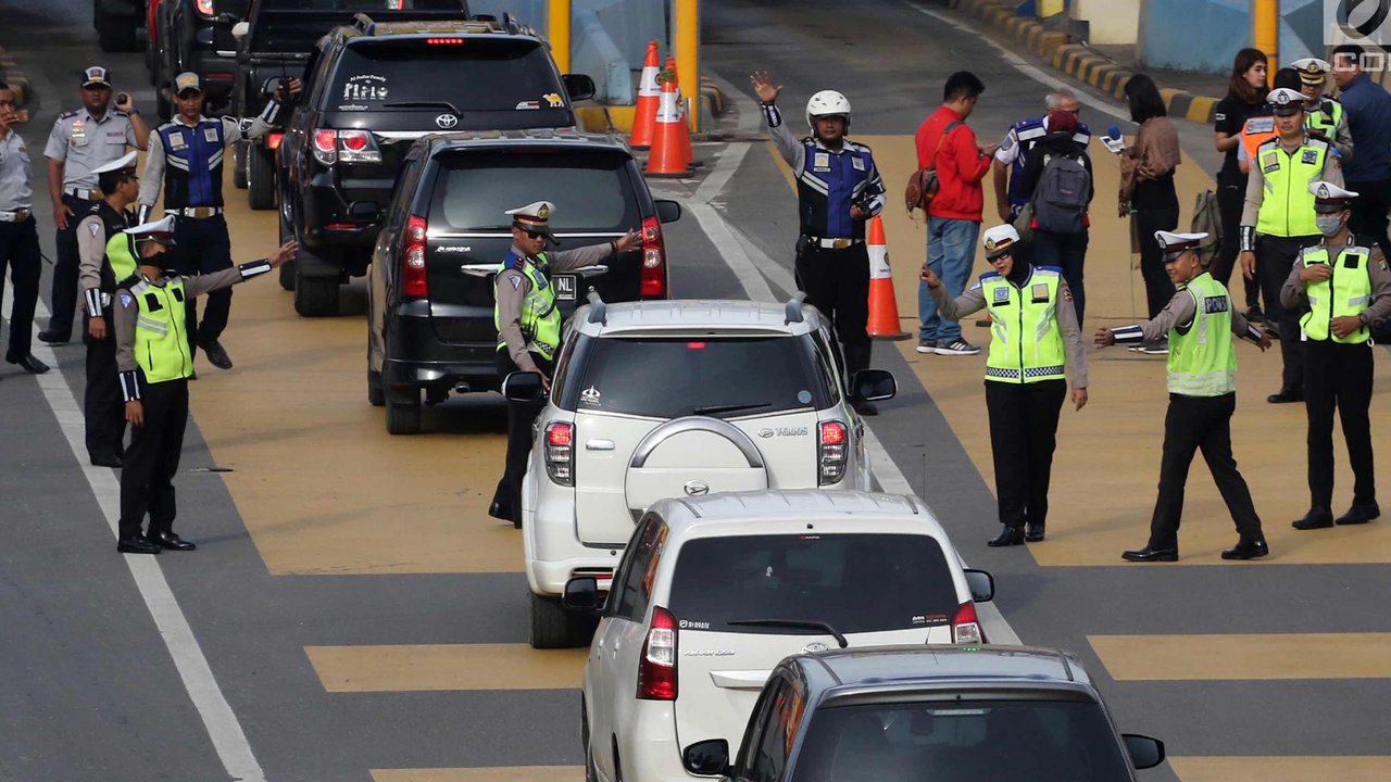 Petugas mengarahkan kendaraan berplat genap berputar balik di Gerbang Tol Bekasi Barat 1, Bekasi, Jawa Barat, Selasa (13/3). Hari kedua penerapan ganjil genap, masih banyak kendaraan berputar balik di gerbang tol tersebut. (Liputan6.com/Arya Manggala)