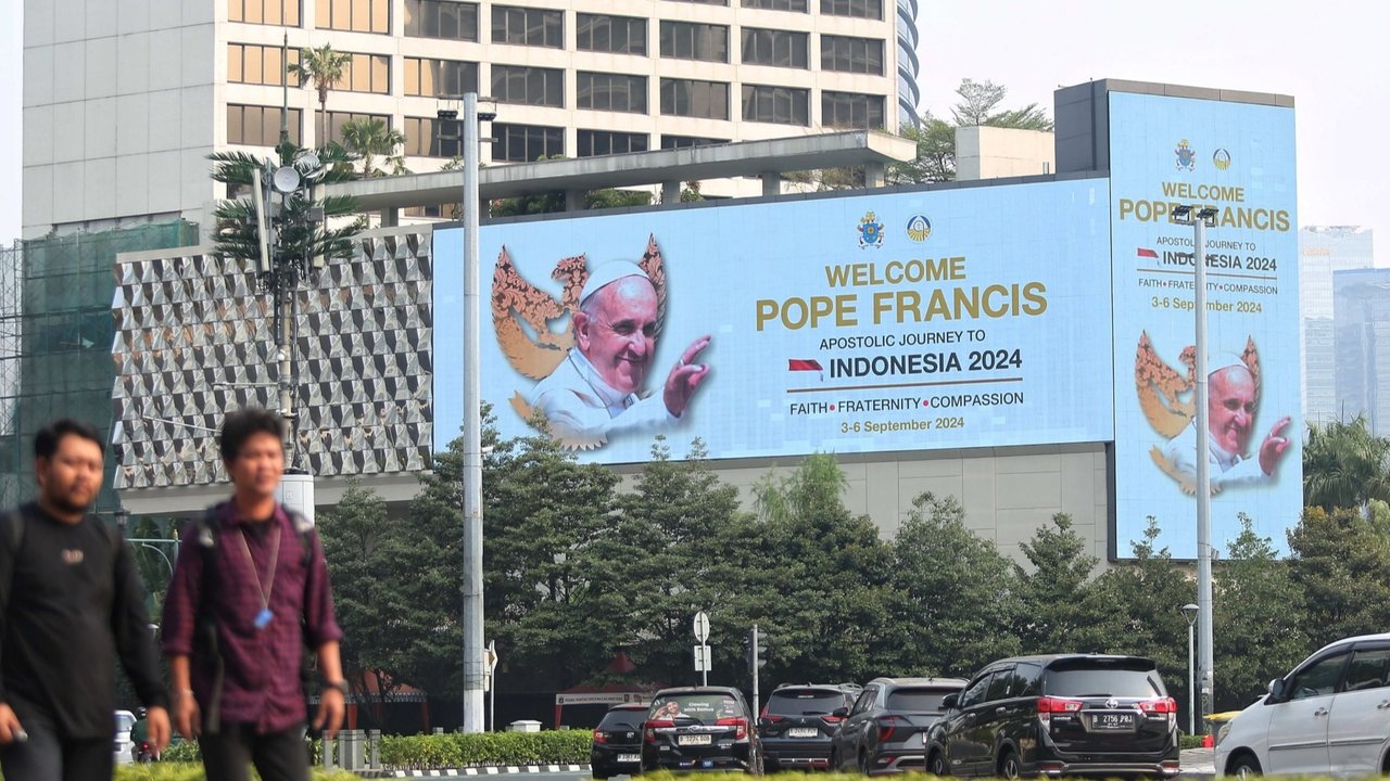 Warga berjalan di depan Layar LED ucapan selamat datang Pope Francis yang terpasang di kawasan Bundaran HI Jakarta, Minggu (1/9/2024). Ucapan tersebut untuk menyambut kunjungan Paus Fransiskus ke Indonesia pada 3-6 September 2024.