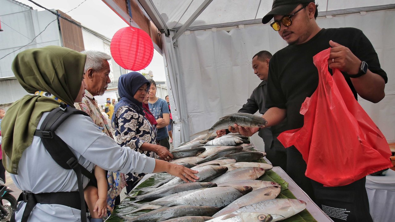 Sejumlah pengunjung memilih ikan bandeng saat berbelanja dalam Festival Bandeng Rawa Belong, Jakarta, Selasa (28/1/2025).