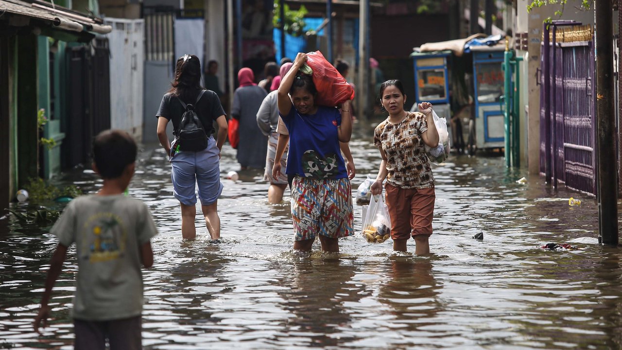 Warga melintasi banjir setinggi lutut orang dewasa yang merendam pemukiman penduduk di kawasan Cengkareng Barat, Jakarta Barat, Kamis (30/1/2025).