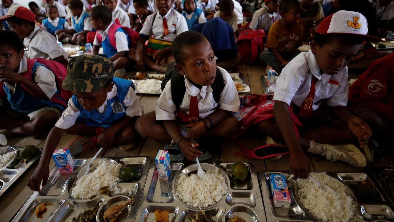 Murid-murid sekolah dasar antri menunggu giliran untuk menyantap menu makan bergizi gratis perdana serta distribusinya kepada pelajar di SD Santo Michael Bilogae, Distrik Sugapa, Kabupaten Sugapa, Intan Jaya, Papua Tengah, Senin (20/1/2025).