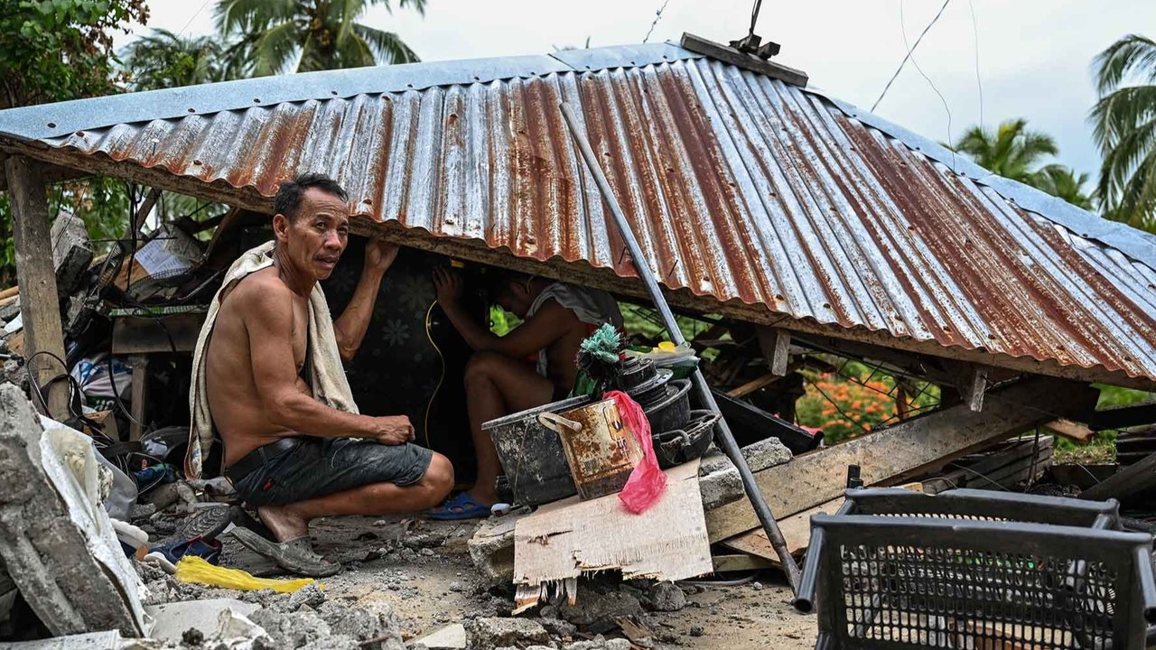 Warga  mencari barang-barang di sebuah rumah yang runtuh di Manay, Provinsi Davao Oriental, Sabtu, (11/10/2025).