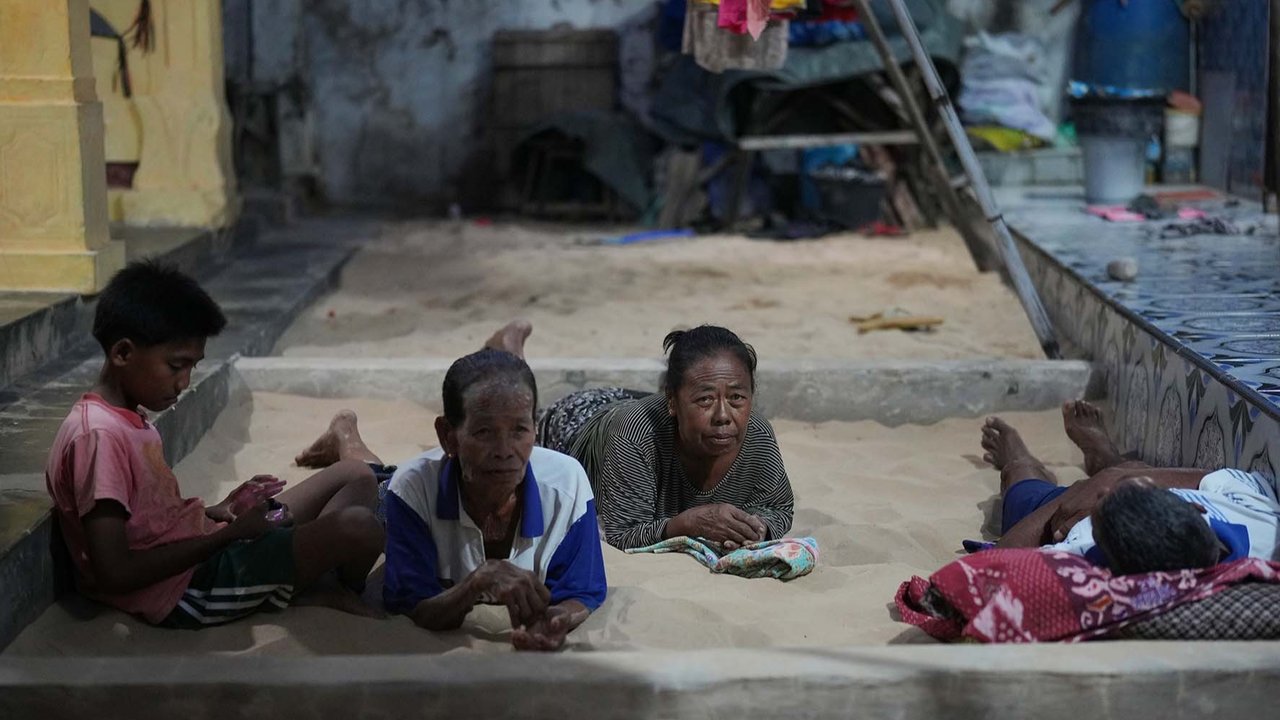 Satu keluarga duduk  dan terbaring di bak pasir di rumahnya di Desa Legung Timur, Sumenep, Pulau Madura, Indonesia, Selasa (09/09/2025).