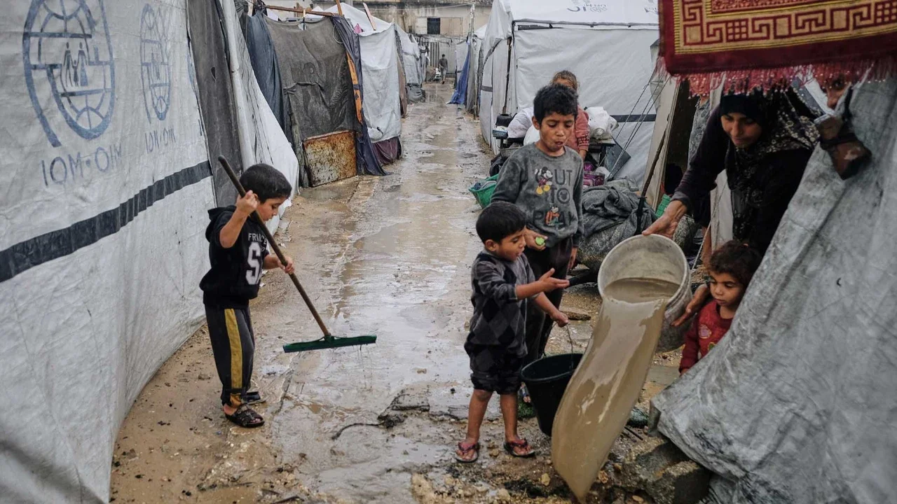 Warga Palestina membersihkan air dari tenda mereka yang terendam banjir di kamp sementara setelah hujan deras di Kota Gaza, Selasa, (25/11/2025).