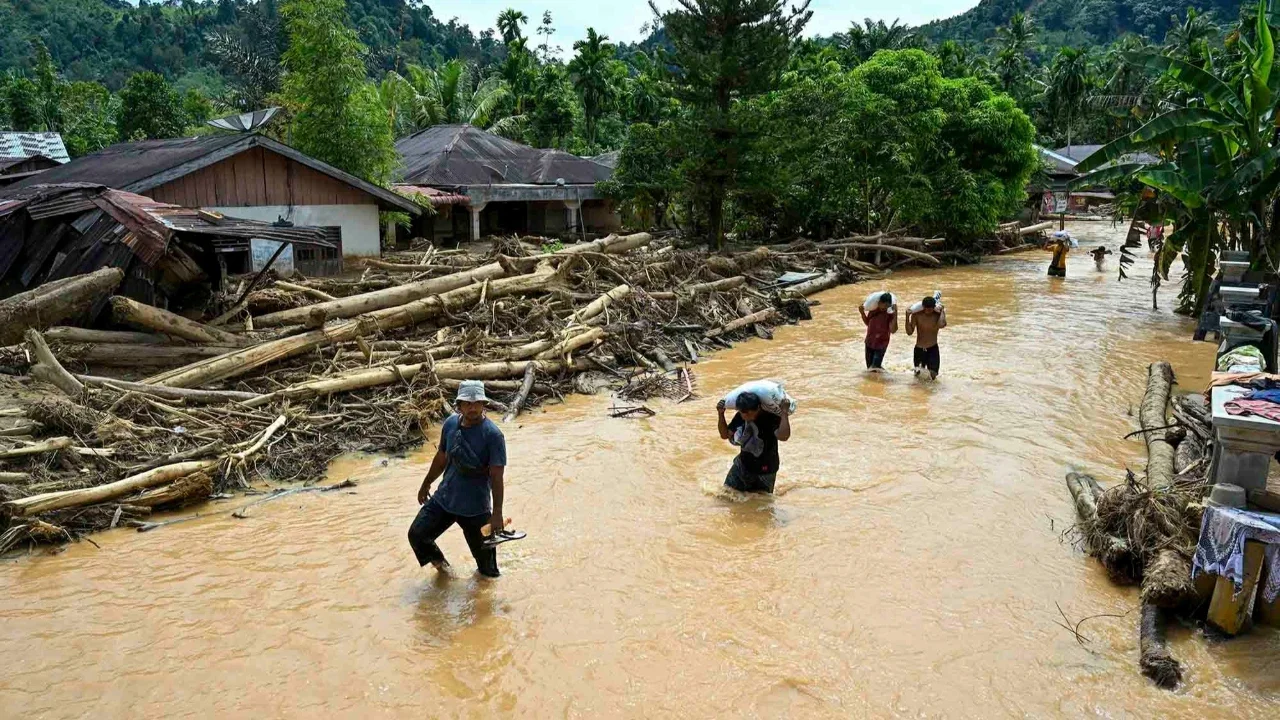 Warga berjalan di tengah banjir bandang di Desa Tukka, Tapanuli Tengah, Provinsi Sumatera Utara, Selasa (02/12/2025).