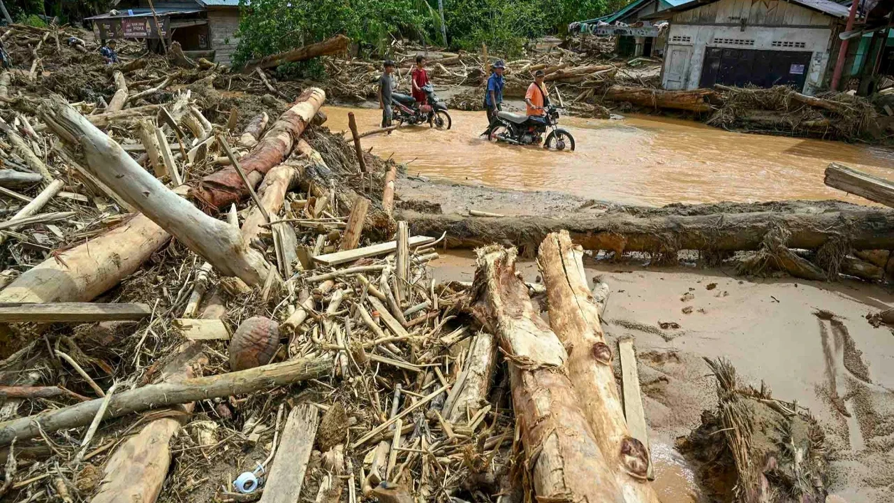 Warga berjalan di tengah banjir bandang di Desa Tukka, Tapanuli Tengah, Provinsi Sumatera Utara, Selasa (02/12/2025).