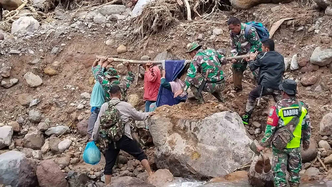 Anggota Koramil 05/Permata TNI AD mengevakuasi sepasang lansia dari wilayah terisolir menuju Puskesmas Buntul di Gucci Desa Burni Pase, Kecamatan Permata, Kabupaten Bener Meriah, Kamis (11/12/2025).