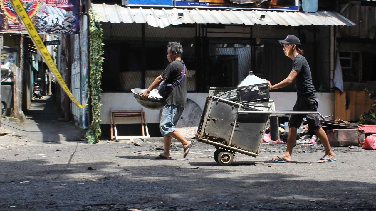 Pedagang mengamankan sisa barang yang tersisa dari warung usai dibakar sekelompok massa di Kalibata, Jakarta, Jumat (12/12/ 2025