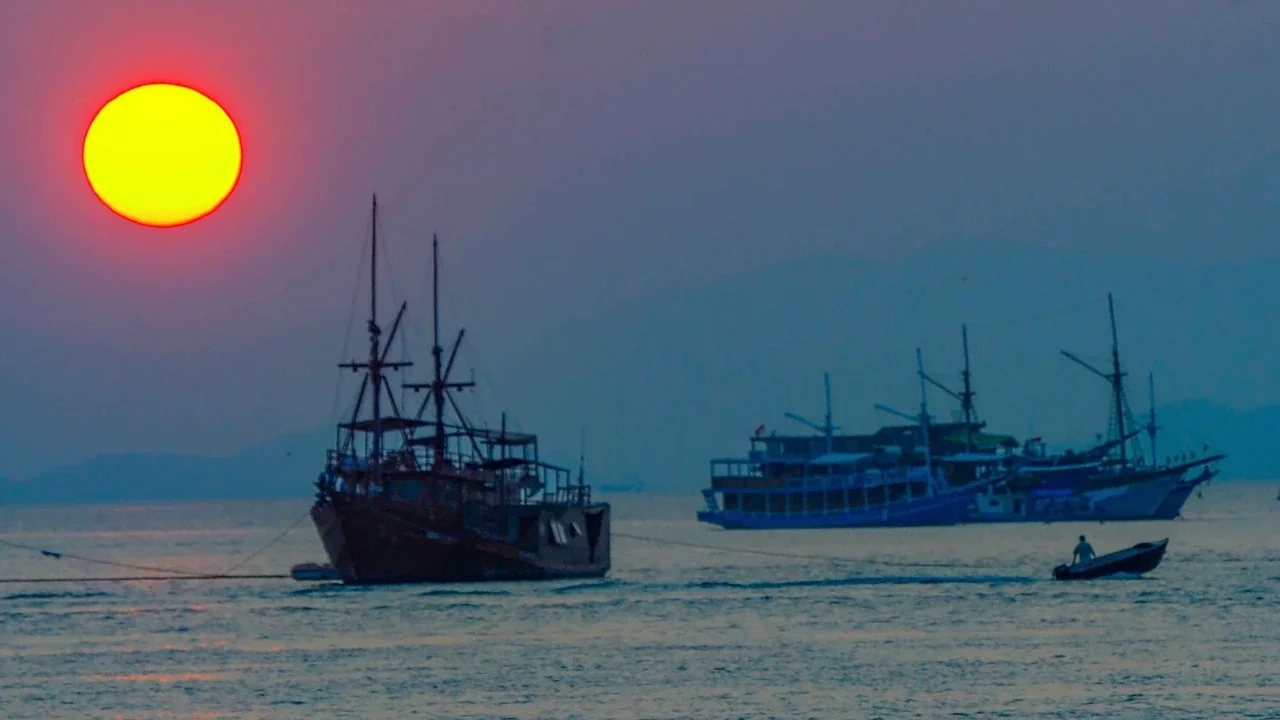 Perahu melintasi matahari terbenam di Labuan Bajo, NTT