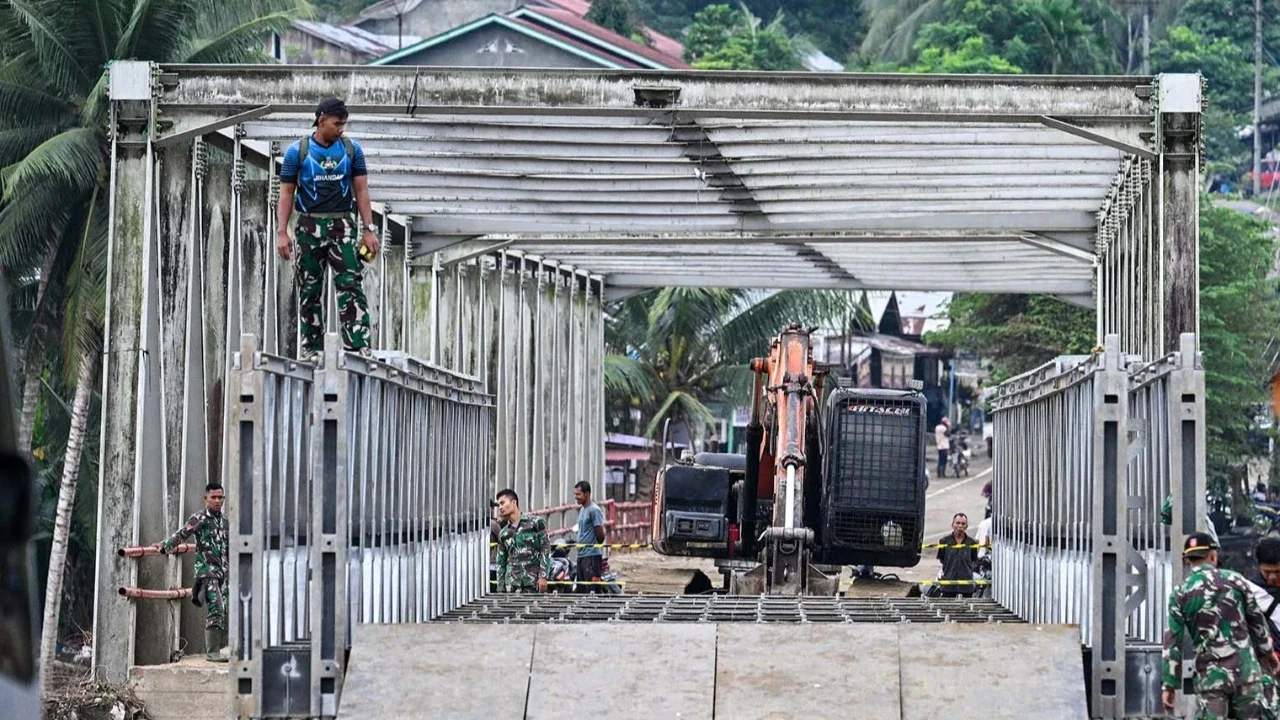 Prajurit TNI Kodam Iskandar Muda bersama petugas Kementerian Pekerjaan Umum menyelesaikan pembangunan jembatan bailey untuk memperbaiki sementara jembatan Juli yang rusak akibat bencana banjir bandang di Bireuen, Aceh, Minggu (14/12/2025),