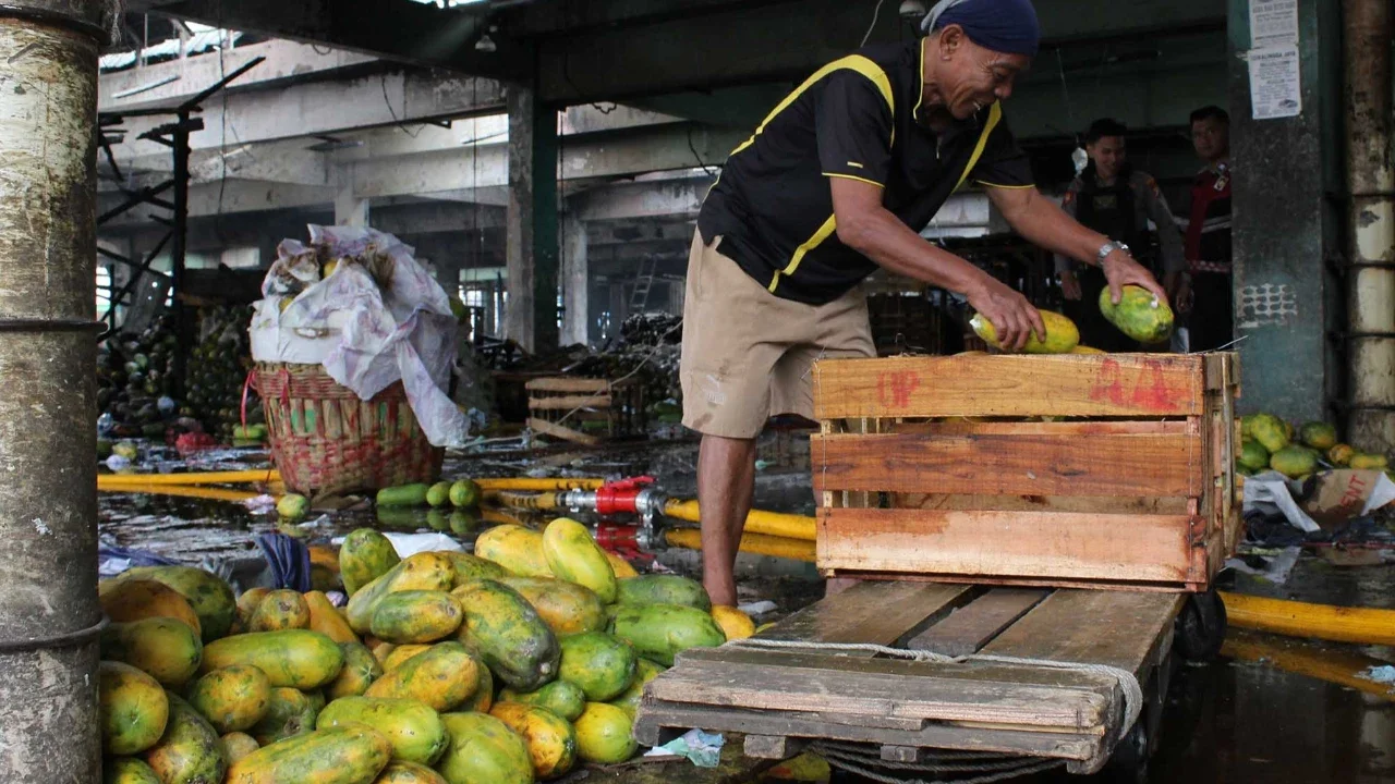 Pedagang menyelamatkan buah dagangannya saat kebakaran di Pasar Induk Kramat jati, Jakarta Timur, Senin (15/12/2025).