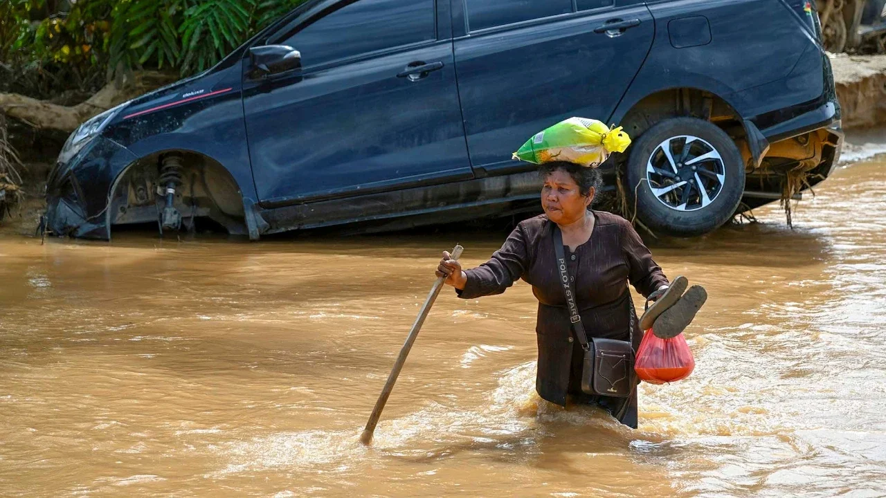 Warga berjalan di tengah banjir bandang di Desa Tukka, Tapanuli Tengah, Provinsi Sumatera Utara, Selasa (02/12/2025).