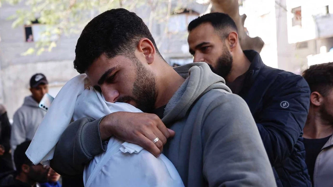 Seorang pria Palestina menggendong jenazah adiknya yang berusia 5 bulan, Ahmed Al-Nader, yang dilaporkan tewas sehari sebelumnya bersama anggota keluarga lainnya dalam serangan artileri Israel terhadap sebuah sekolah yang dijadikan tempat perlindungan di lingkungan Tuffah, Kota Gaza, Sabtu (20/12/2025).
