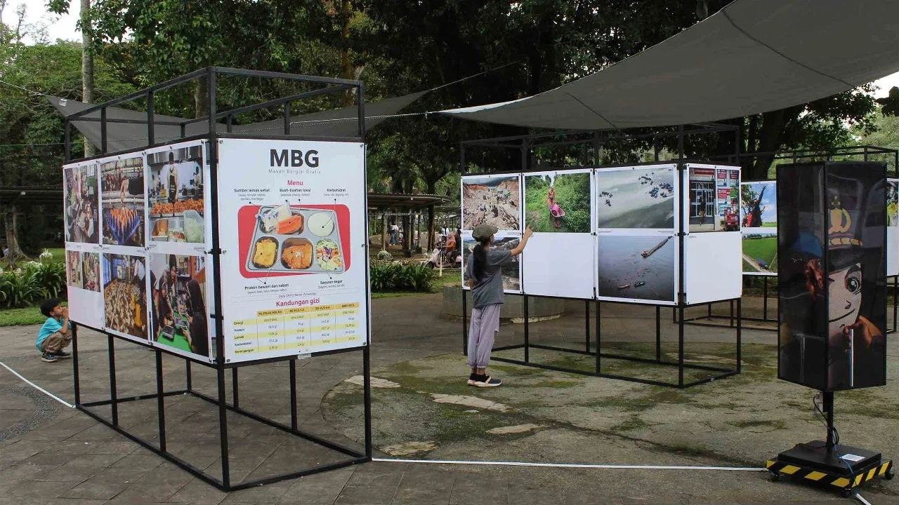 Pengunjung menyaksikan beragam karya jurnalistik dalam pameran Haluan Merah Putih Roadshow yang digelar di Selasar Kantin Taman Margasatwa Ragunan, Jakarta Selatan, Selasa (24/12/2025).