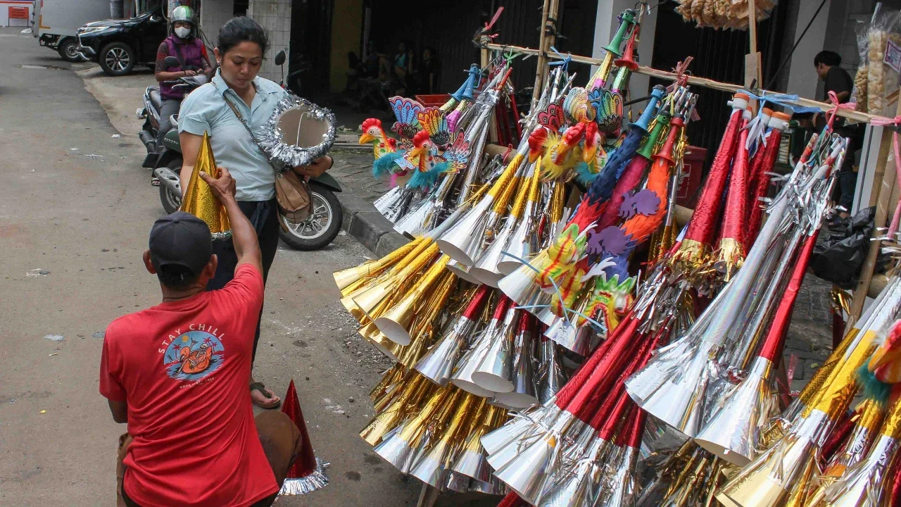 Pedagang melayani pembeli terompet dagangannya di kawasan Glodok, Jakarta, Selasa (30/12/2025