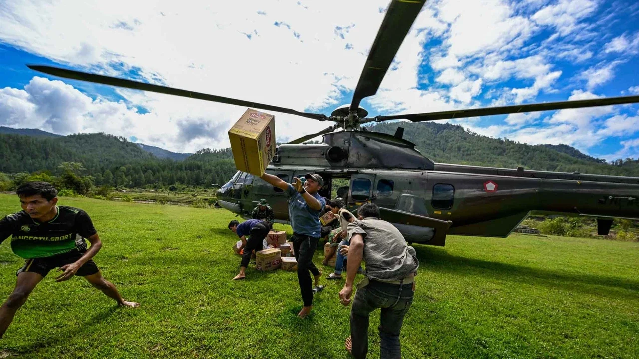 Warga membawa bantuan yang didistribusikan helikopter  TNI AU di wilayah terdampak banjir di Kabupaten Bener Meriah, Provinsi Aceh,Kamis (04/12/2025).