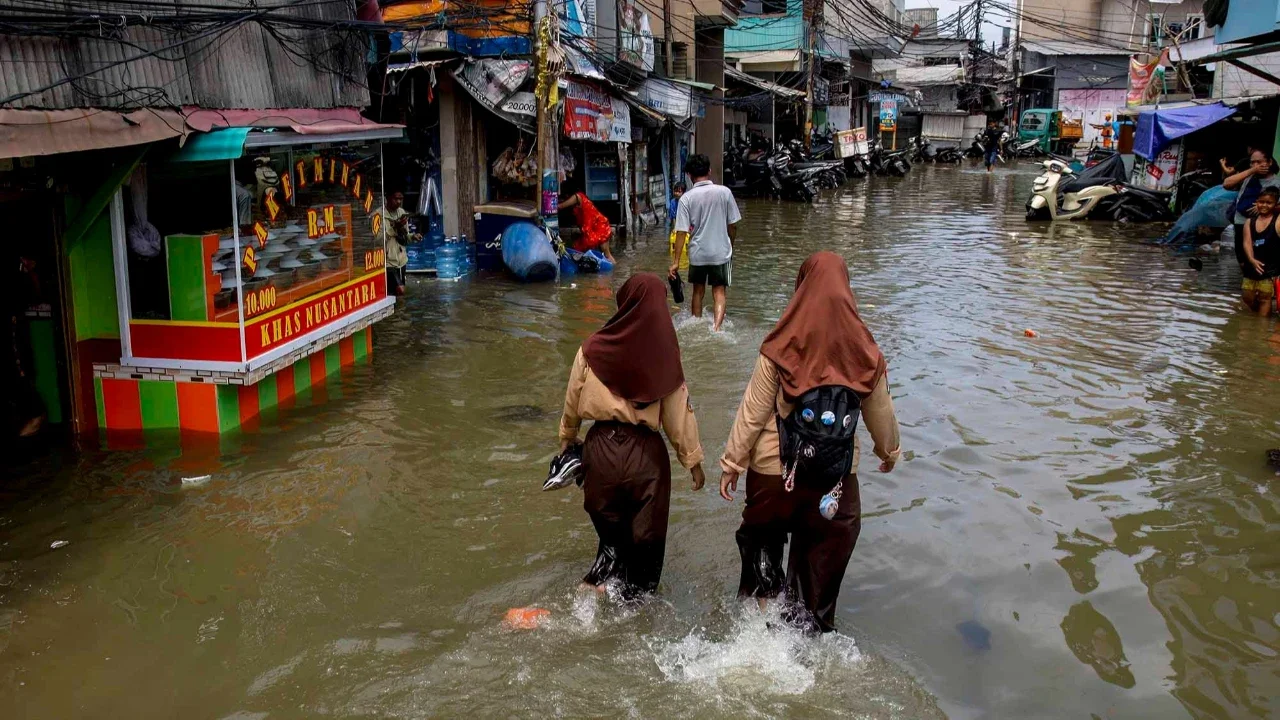 Warga melintasi genangan saat banjir rob di Muara Baru, Jakarta, Sabtu (06/12/2025).