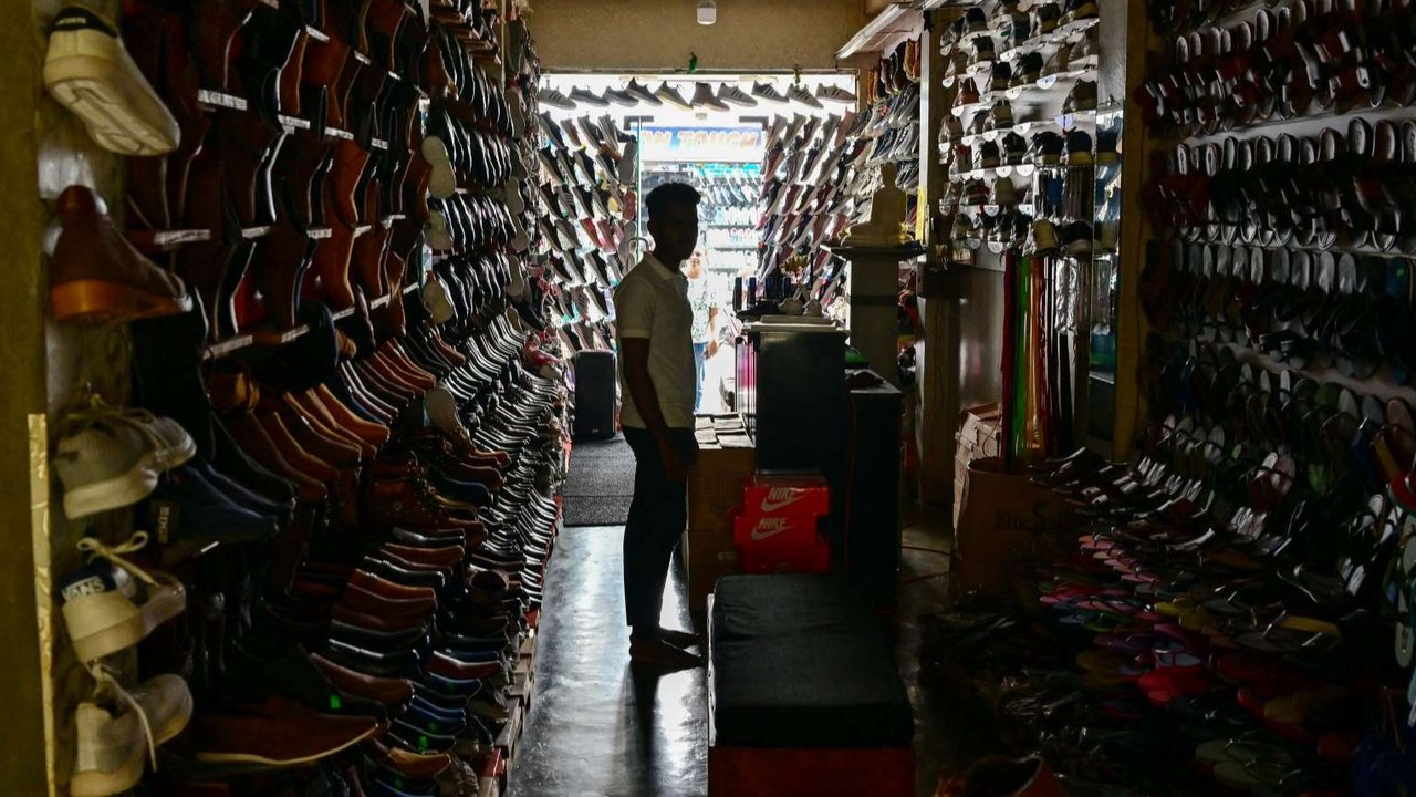 Seorang pria menunggu pelanggan di toko alas kaki yang redup selama pemadaman listrik nasional gara-gara monyet di Galle, Sri Lanka, pada 9 Februari 2025.