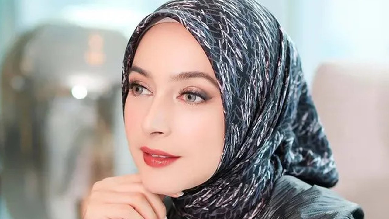 Seperti potret ini, aktris  37 tahun itu mengenakan hijab dengan motif berwarna putih dan abu-abu. Riasan yang bold yang berfokus pada bagian mata dan bibir beri kesan glamor pada penampilann
